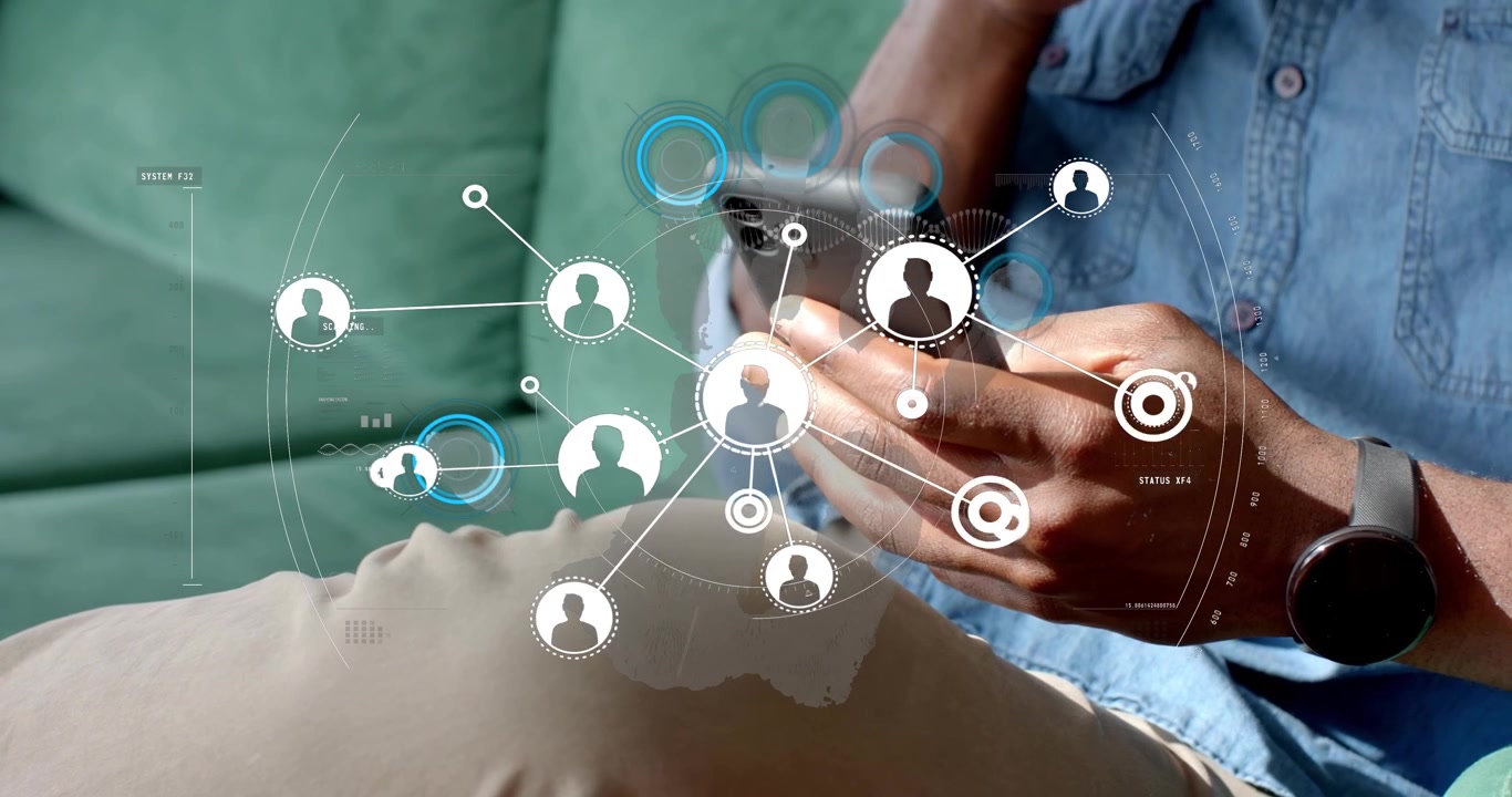 Man tapping smartphone, holding mug on couch accessing health network overlay over pregnant abdomen