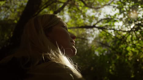 Süße-Blonde-Frau-Blickt-Neugierig-Auf-Den-Wald-Mit-Hellem-Sonnenlicht,-Porträtaufnahme