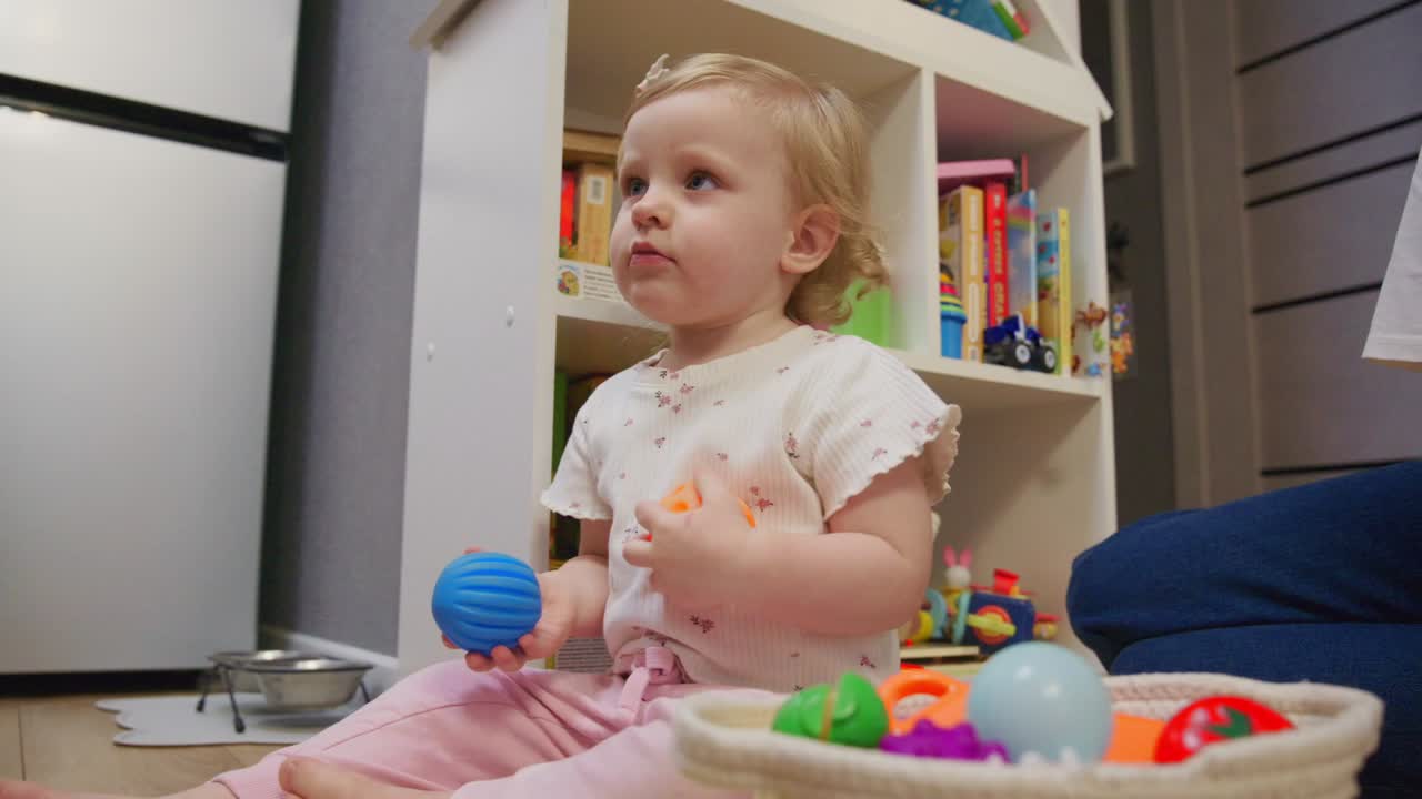 Cute Toddler Girl Playing with Colorful Balls on the Floor