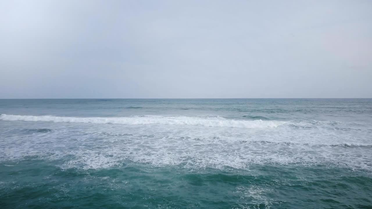 아름다운 파란색 개방된 바다에서 거품이 나는 물결의 드론 풍경. 숨을  수 있는 해경과 구름이 가득한 하늘 지평선 파노라마.