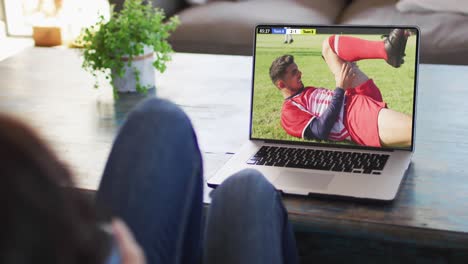 Man-using-laptop-with-diverse-male-soccer-players-playing-match-on-screen