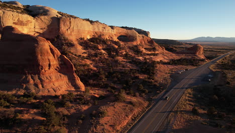 aerial view of uta state route road natural arch and red sandstone cliffs, drone shot