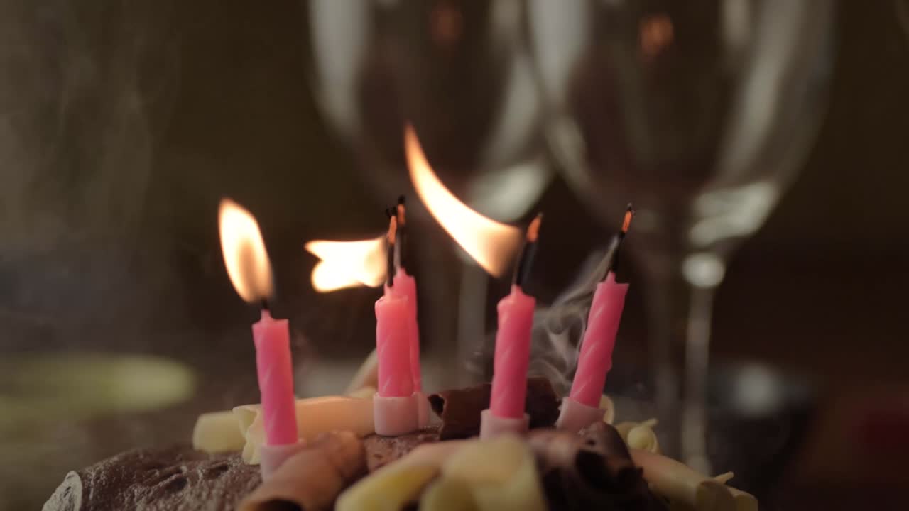 soplando velas en pastel de cumpleaños de chocolate.