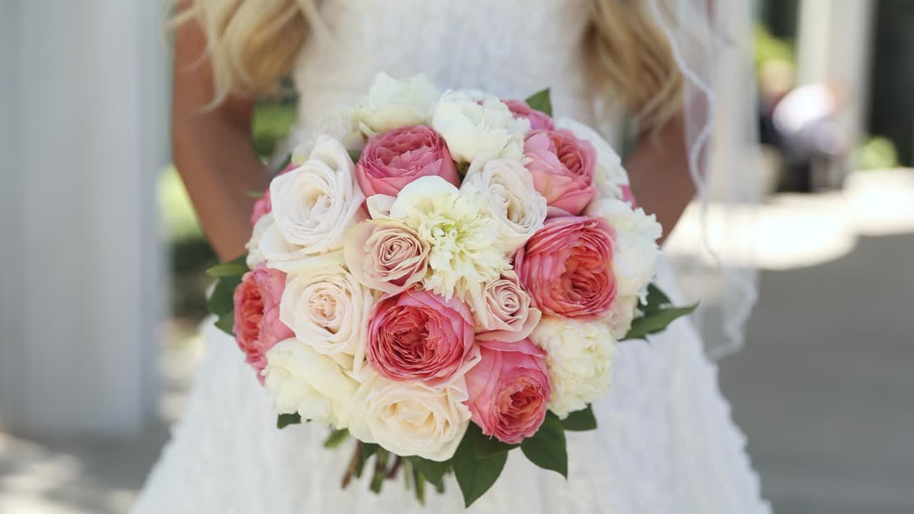 Primo piano della sposa che tiene un grande e colorato bouquet da sposa composto da rose