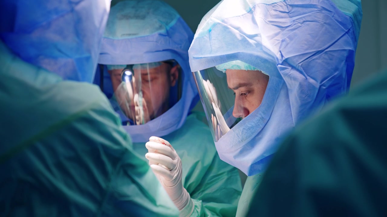 Equipe chirurgica maschile al lavoro in chirurgia traumatologica. Medici caucasici con elmetti protettivi collaborano all'intervento.