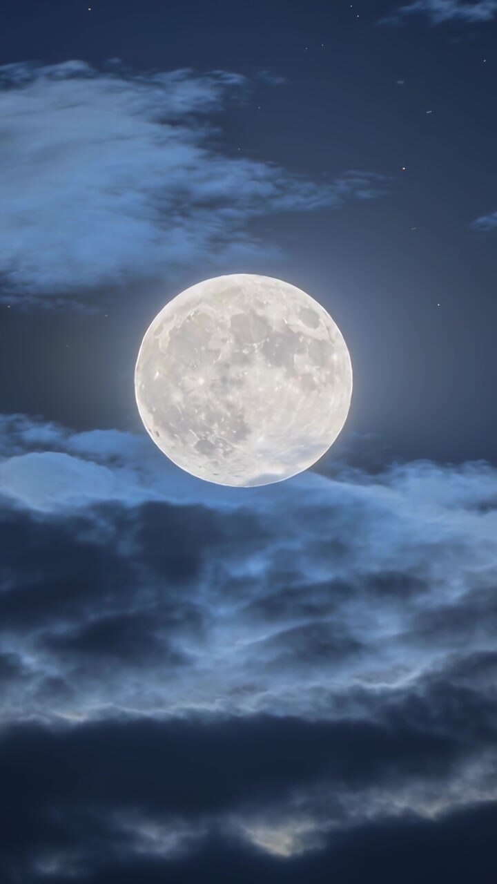 Vídeo vertical: Camadas de nuvens flutuantes movendo-se sobre a lua cheia no céu noturno, criando um breve véu.