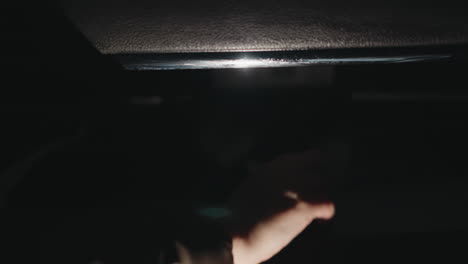 first-person view of a hand with glitter nail polish opening a car glove compartment,and brought out an eyes glass the scene is dark, highlighting the action of the hand. blurry