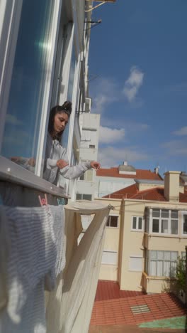 young woman drying clothes on a balcony