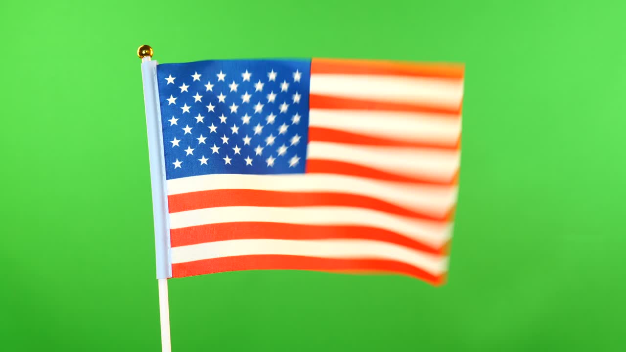la bandera de los estados unidos en el mástil sobre un fondo verde. la bandera estadounidense ondeando en el viento.