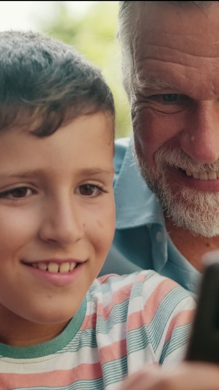 Grandfather and Grandson Smiling While Using Smartphone Together