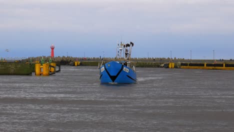 barco de pesca azul entra en el puerto de kolobrzeg, polonia