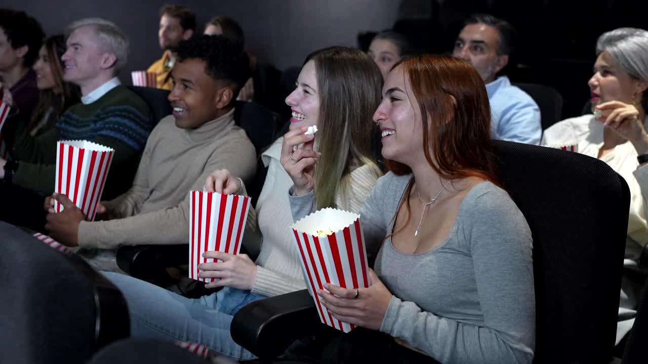 People Enjoying a Movie at the Theater with Popcorn