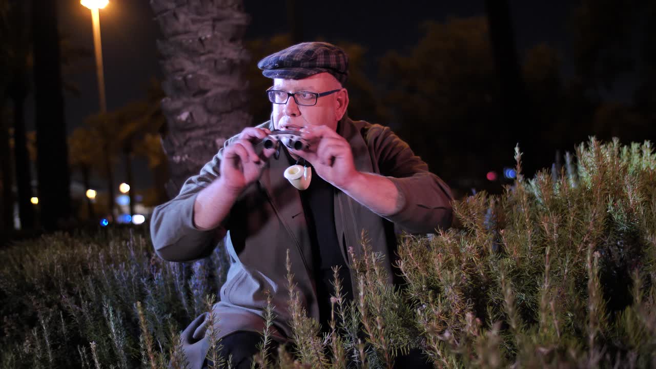 hilarante detective privado por la noche se esconde y observa a través de binoculares en busca de pistas