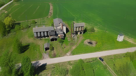 upward tilting drone footage shows a farm with silos between the pastures