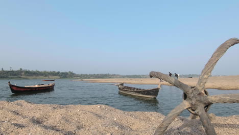 Time-lapse-of-wooden-canoes-moored-in-river,-unrecognizable-people-passing-by