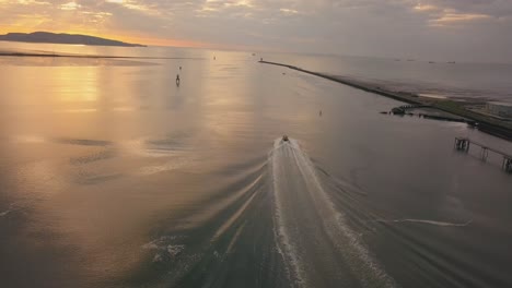 Tiro-De-Seguimiento-Aéreo,-Barco-Piloto-Saliendo-Del-Puerto-Al-Atardecer