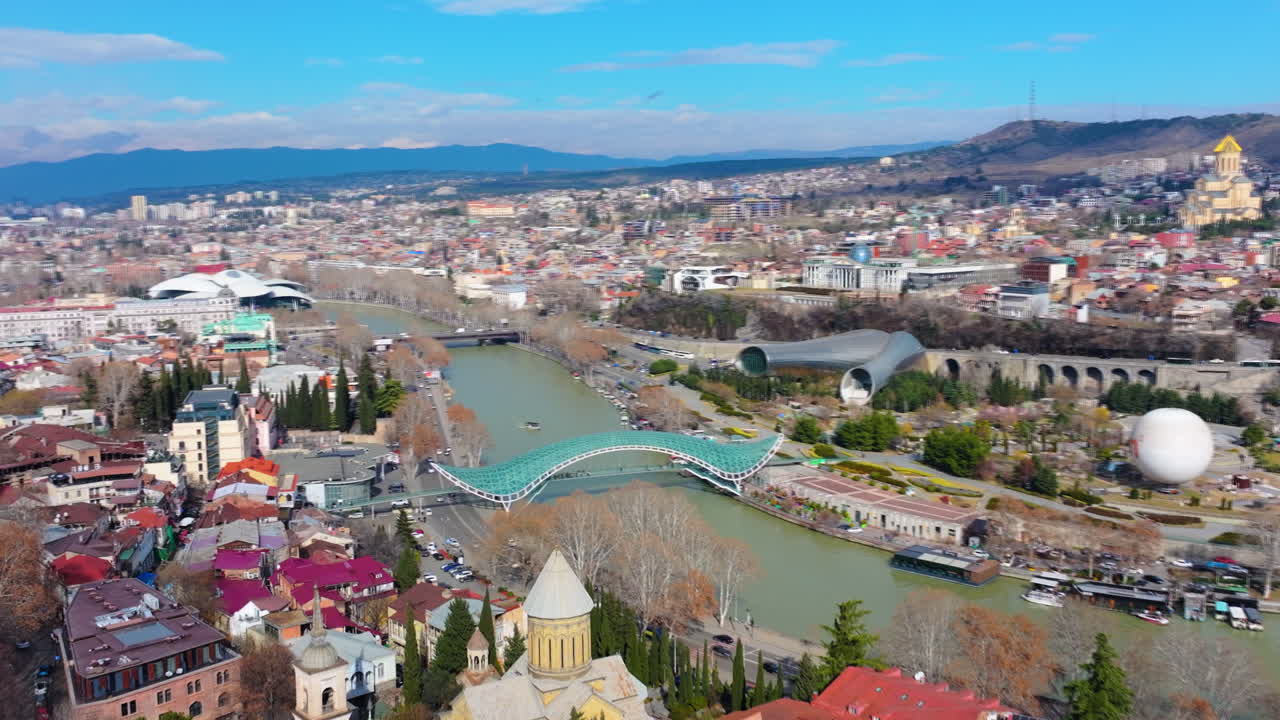 4K filmové záběry z dronu letícího nad Mostem míru v Tbilisi, odhalující elegantní architektonický design překračující řeku Kuru_06