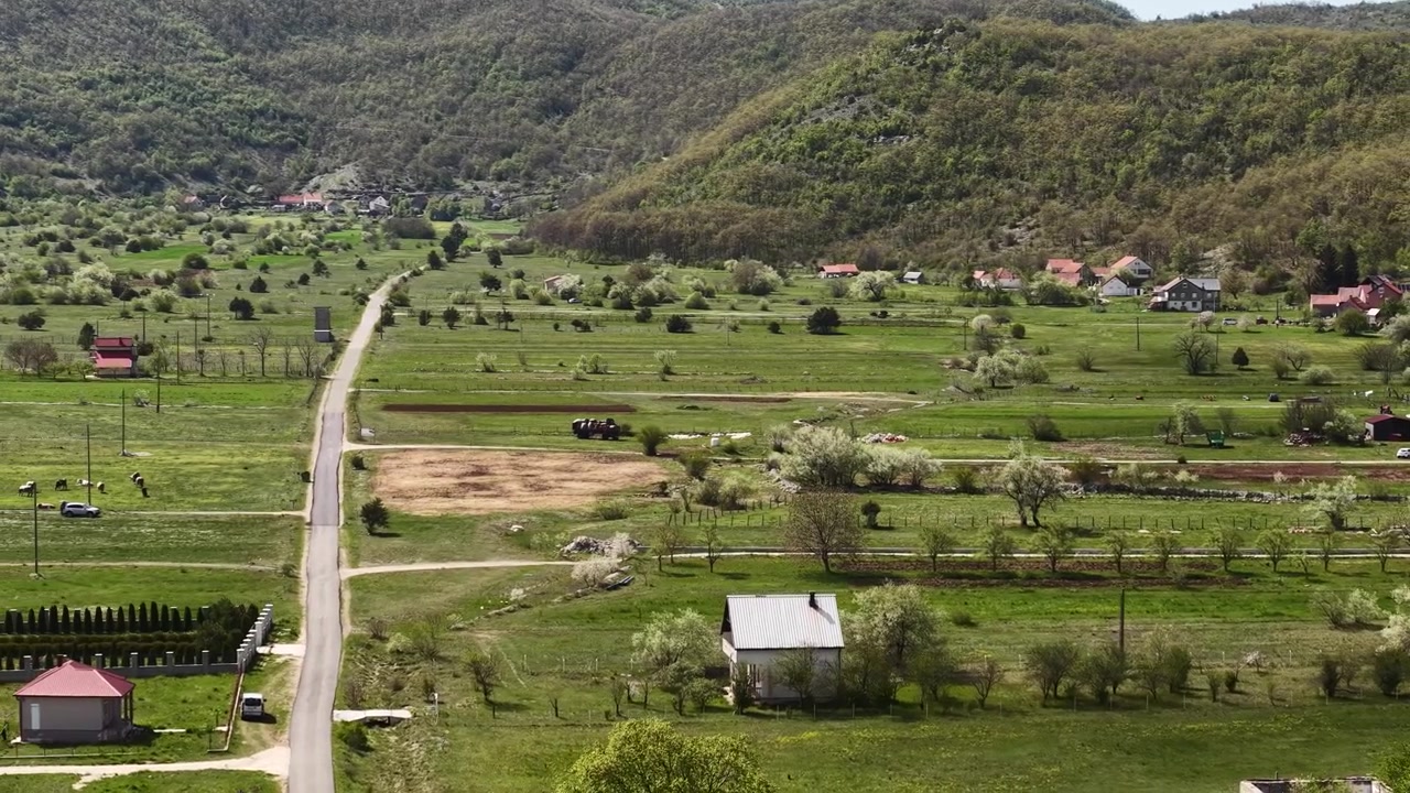 Rekaman drone lahan pertanian dan ladang di bawah pegunungan di Montenegro.