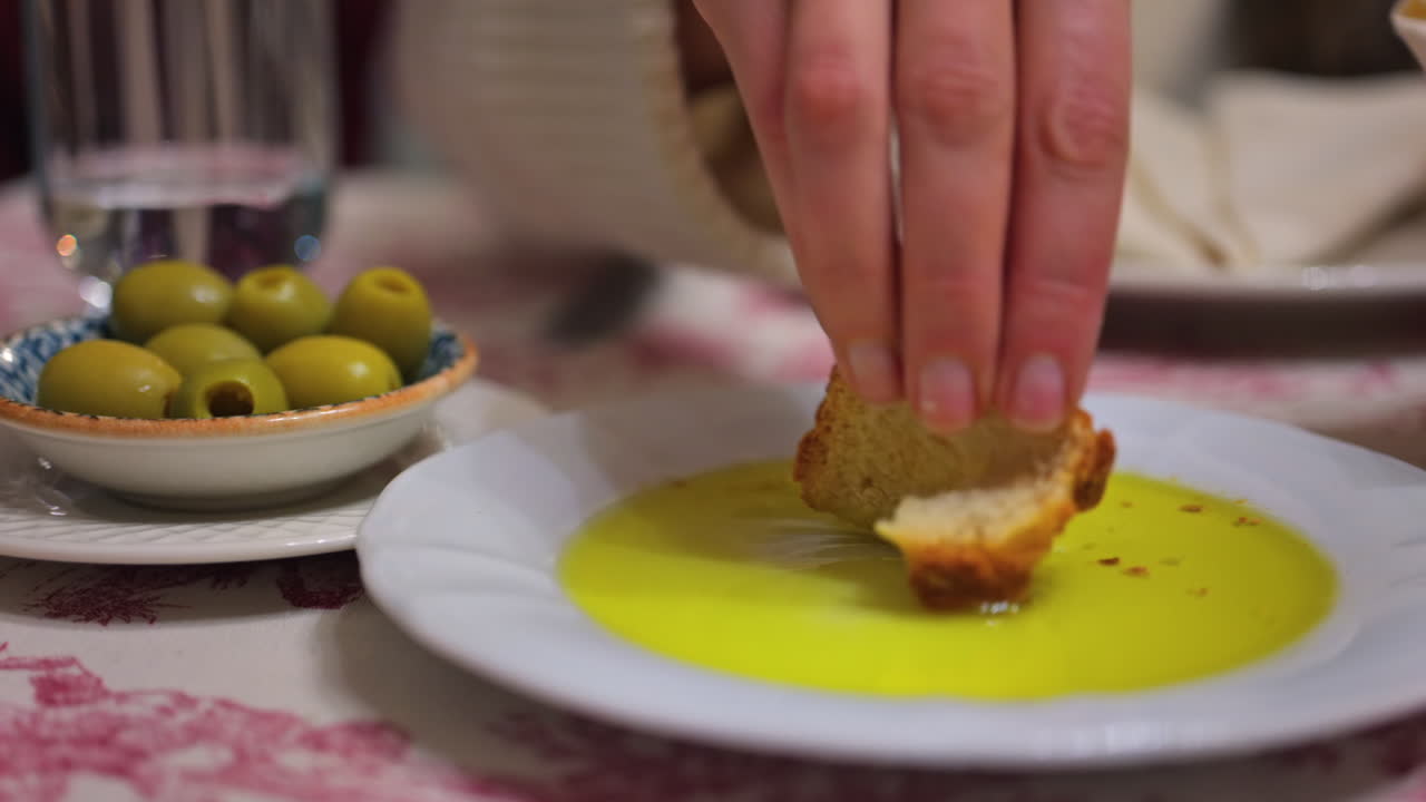 Close up of a woman dipping bread in olive oil and eating it at a restaurant