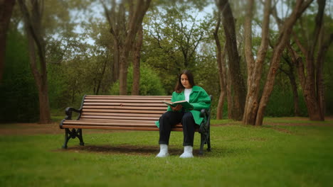 woman reading a book on a park bench