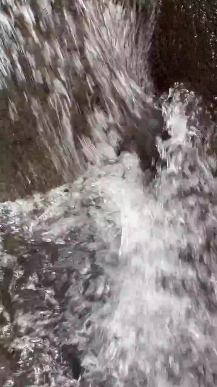 Primo piano di acqua che scorre su rocce scure
