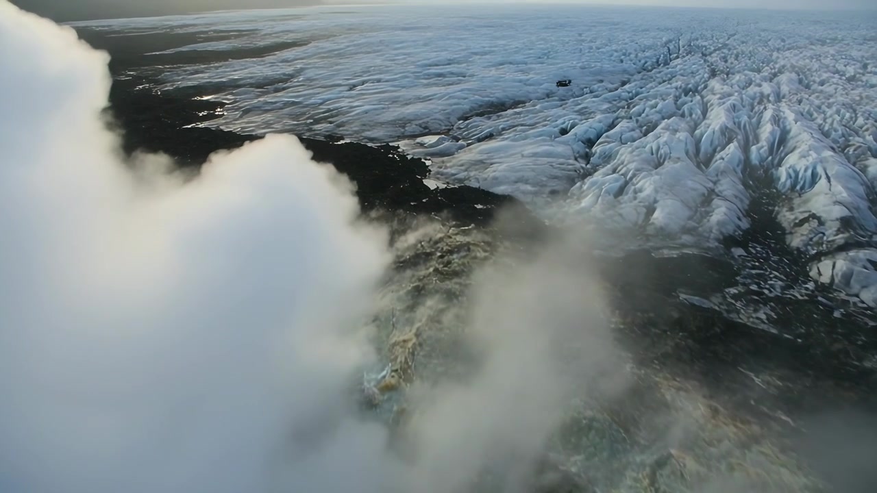 Spårar tjockt lågt molntäcke som flyttar sig, avslöjar sprucken glaciär och klippig kustlinje, utrymme för text.