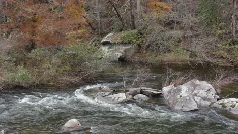 Drone-shot-of-river-flowing-around-rocks-in-late-fall-in-western-North-Carolina