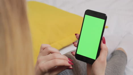 mujer sosteniendo un teléfono inteligente con pantalla verde