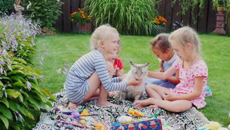 children play with a cat in the yard