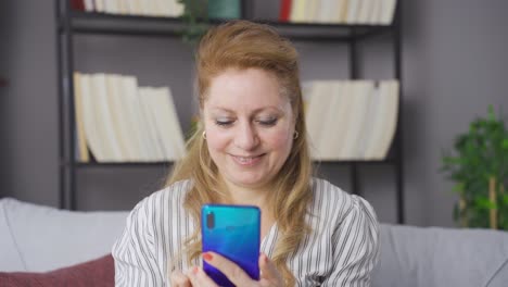 Mature-old-woman-browsing-social-media-or-playing-games-on-her-phone-at-home.