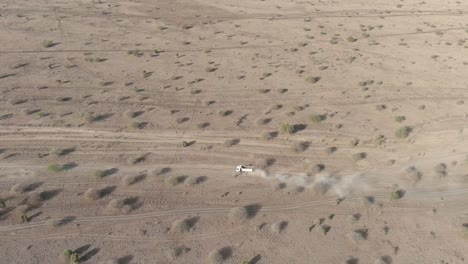 an aerial view of a white truck driving along a dirt road