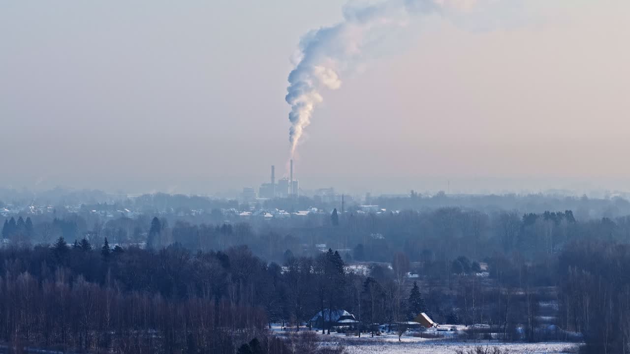Smoke rises over rural winter landscape, conveying industrial impact