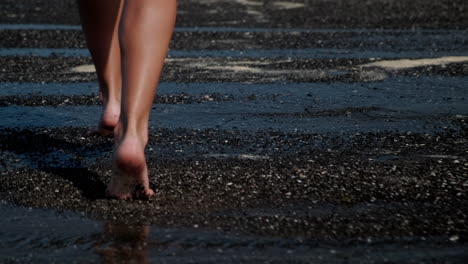 woman's feet walking on wet dark sand beach