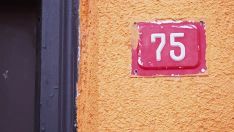 house number 75 on a peach-colored wall