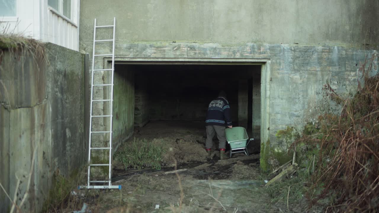 A Man is Using a Shovel to Fill the Wheelbarrow with Soil - Static Shot