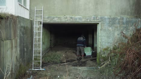 a man is using a shovel to fill the wheelbarrow with soil - static shot