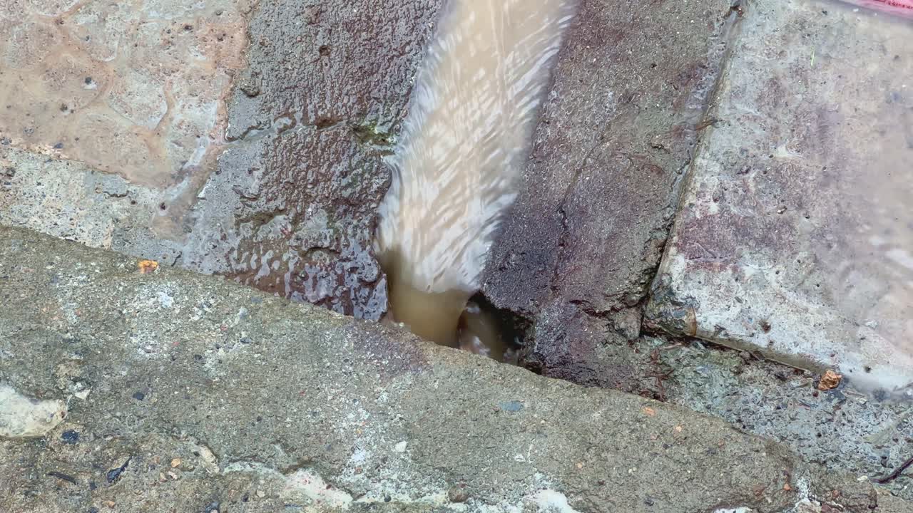 A rainwater flowing through the gutter line made on concrete