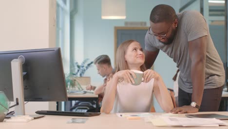 african guy bringing coffee to girl at coworking. happy woman