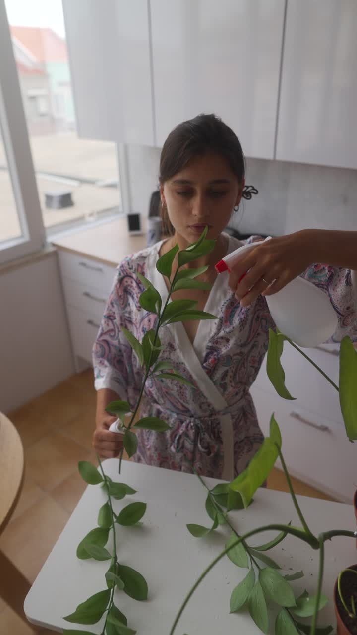 Woman Watering Houseplants in Kitchen