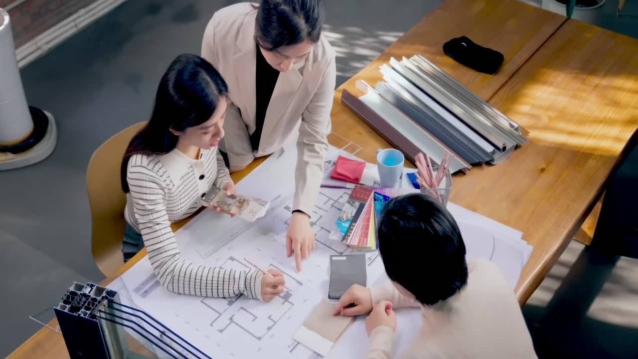 Top down view of Architect team brainstorming idea and planning building design about house project while sitting at table with plan.