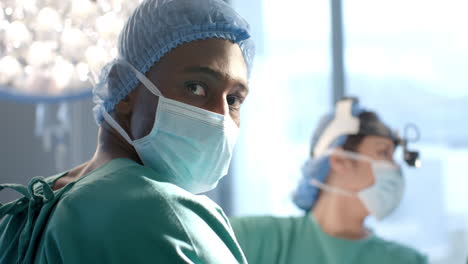 portrait of african american male surgeon operating with colleagues in theatre, slow motion