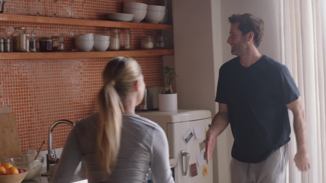 행복한 젊은 부부가 집에서 춤을 추고 재미있는 춤을 함께 즐기며 주말에 관계를 축하합니다.