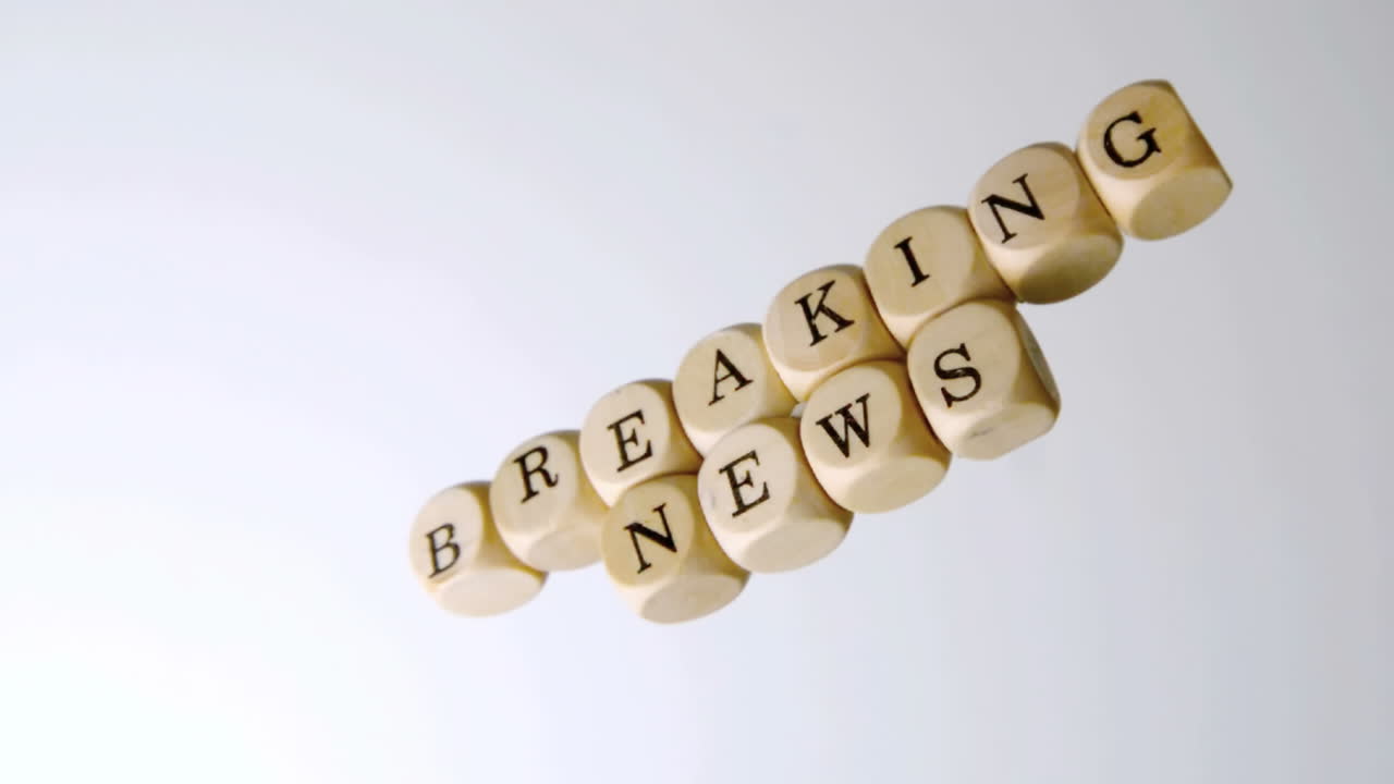 Breaking news spelled out in dice falling on white surface