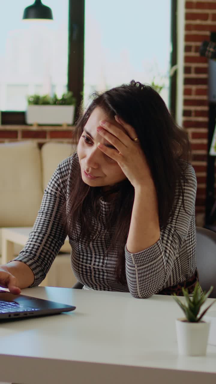 Video verticale: un* freelancer esaust* soffre di malessere e stress mentre lavora al laptop