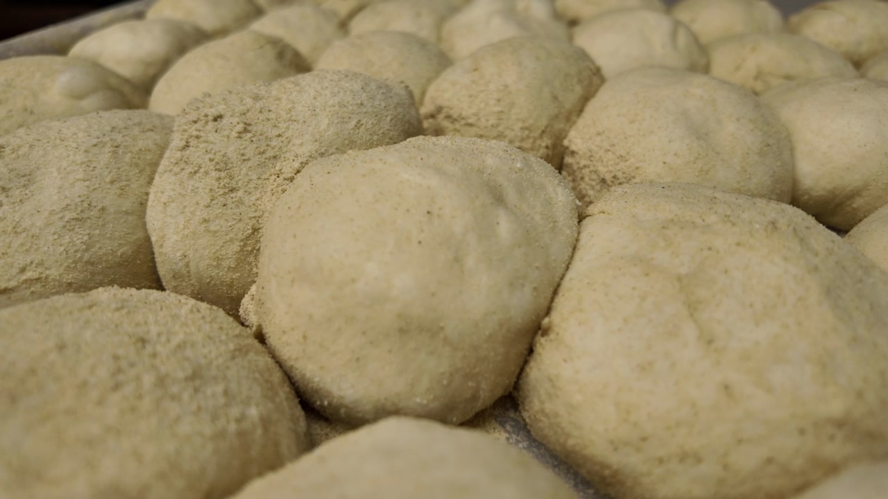 Many Fresh Dough Balls Covered in Flour Ready for Baking