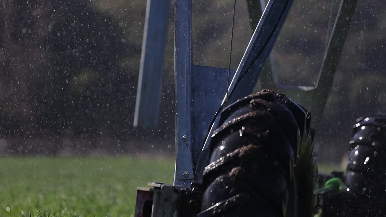 Close-up detail: Wheels from irrigation pivot roll across field, spray