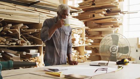 African-american-male-carpenter-drinking-coffee-in-a-carpentry-shop