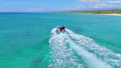 navigating tourist boat with tourists along bahia de las aguilas coastline and shoreline in dominican republic