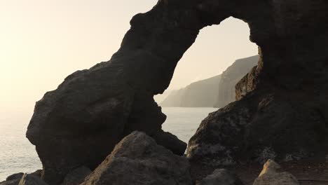 Peeking-through-hole-of-rock-near-the-sea,-dynamic-handheld