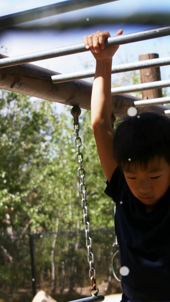 Vertical video: Boy grabbing monkey bar, pulling up, training balance, graphic clearing, education